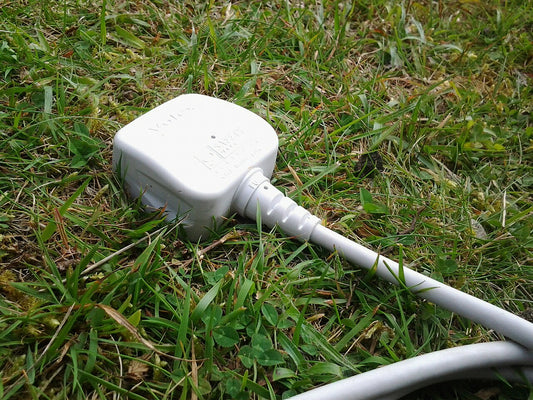 Ein Stecker mit Kabel steckt im Rasen