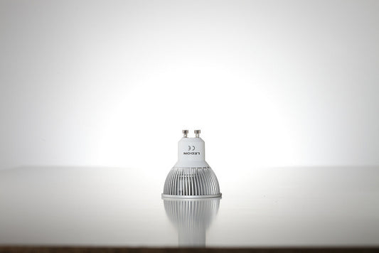 Eine Lampe mit einem GU10-Sockel, bei dem man die untere abgerundete Kante sowie die beiden Metallstifte gut sehen kann.