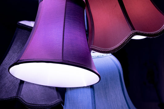 Mehrere, unterschiedlich farbige Lampenschirme in Lila, Blau und Violett leuchten sanft.