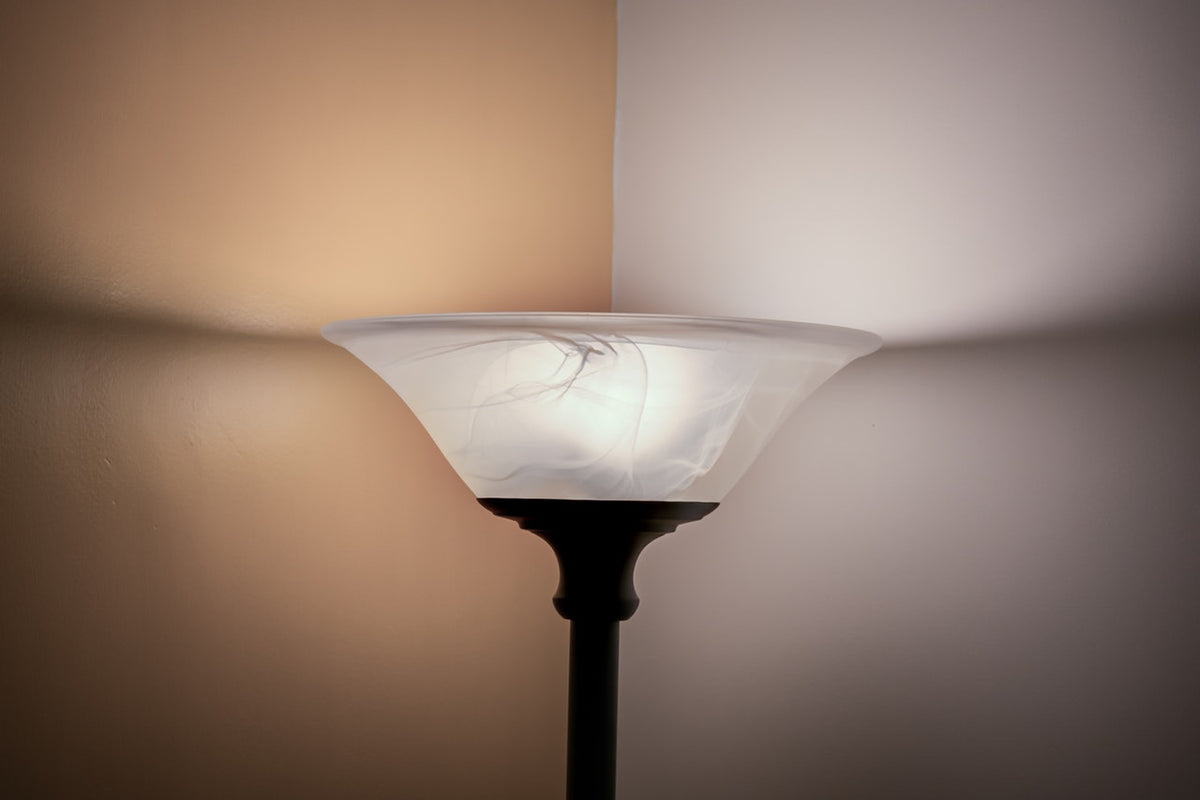 Seiten einer gelben und einer weißen Wand in der Ecke steht ein Deckenfluter, der Licht abstrahlt.