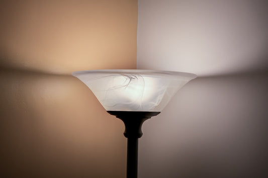 Seiten einer gelben und einer weißen Wand in der Ecke steht ein Deckenfluter, der Licht abstrahlt.
