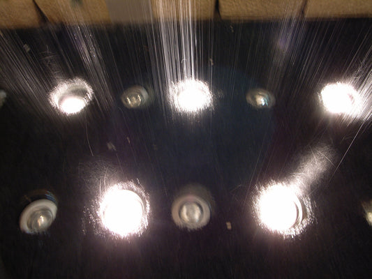 Einbauspots am Boden einer Dusche, während Wasser auf sie fällt - die richtige Beleuchtung für Feuchträume ist wichtig!