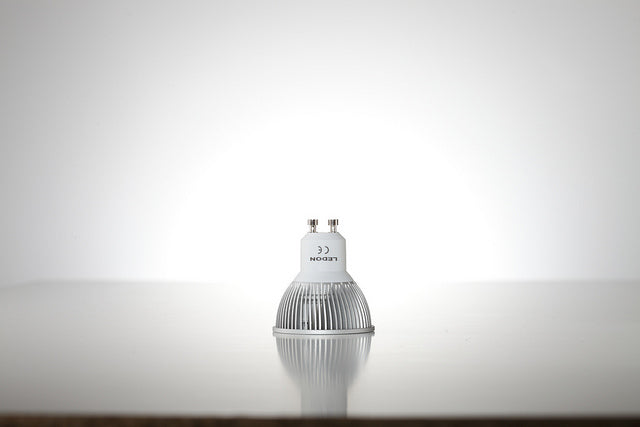 Eine Lampe mit einem GU10-Sockel, bei dem man die untere abgerundete Kante sowie die beiden Metallstifte gut sehen kann.