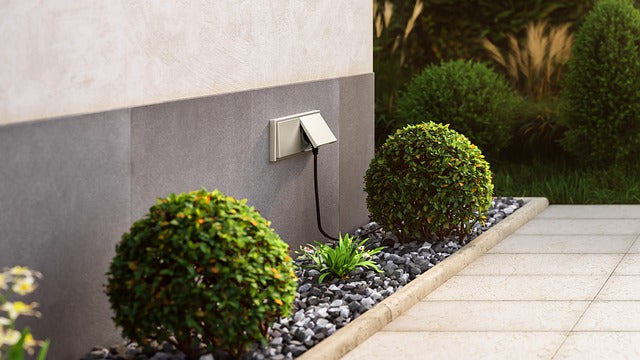 Eine Steckdose an einer Hauswand mit eingestecktem Kabel